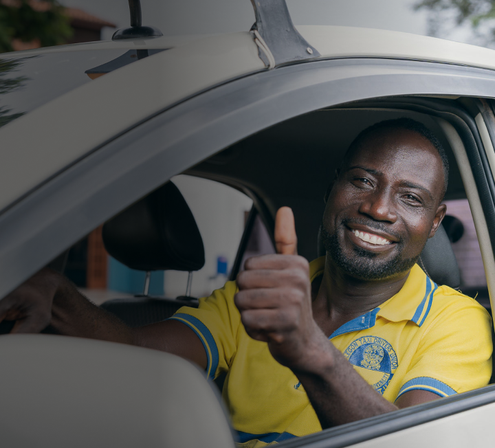 An image of a taxi driver looking at the camera with a smile on his face